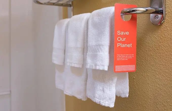Hand towels hanging in hotel bathroom with sustainability message