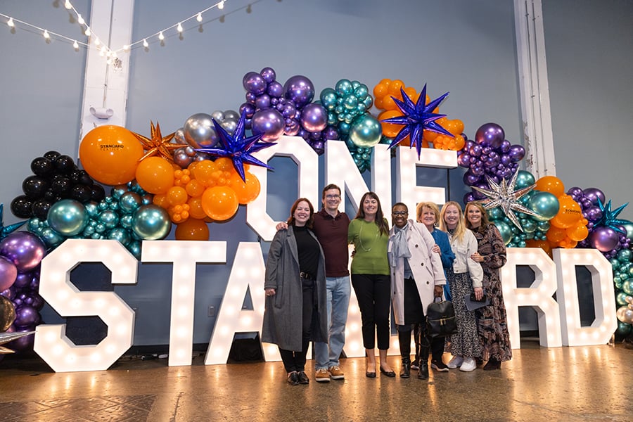 A group of Standard Textile associates in front of the One Standard sign