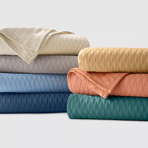 Stack of quilted bed blankets in assorted colors