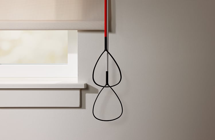Solar window shade with hanging pull cord control next to a window.