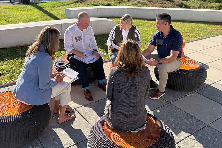 Group seated outdoors discussing notes in a small circle.
