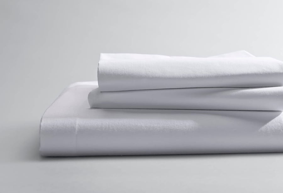 A neatly folded white sheet set arranged in a stack, showcasing a clean and minimal look.