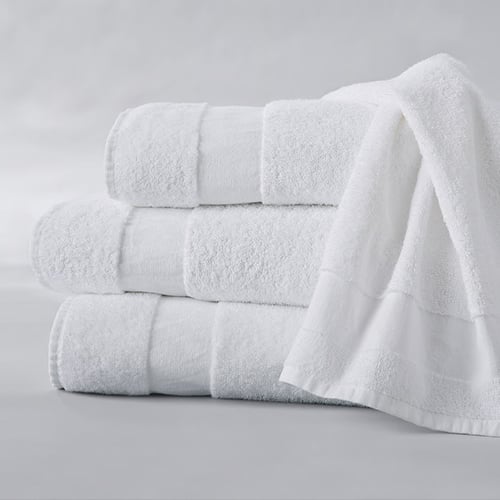 Stack of soft white bath towels with a draped towel on the side