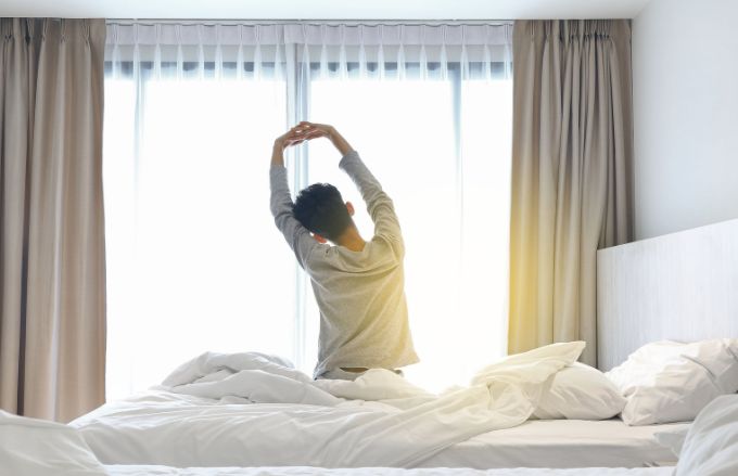 Man waking up and stretching in bed