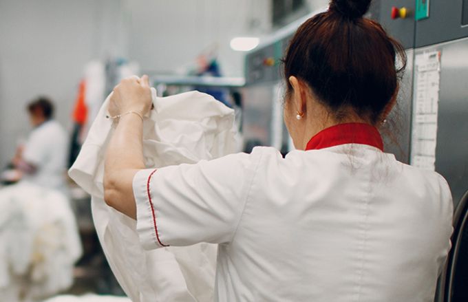 Woman folding laundry in commercial laundry setting