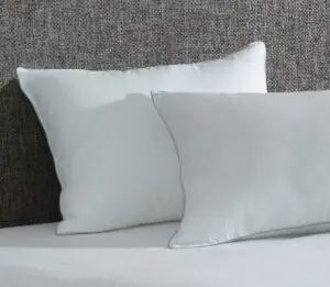 Two AllerEase pillows shown on a bed. These antimicrobial pillows also have a temperature balancing, soft top layer.