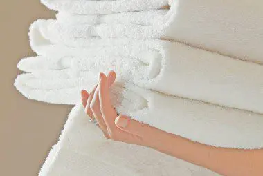 Woman carrying a stack of pre-washed linens.