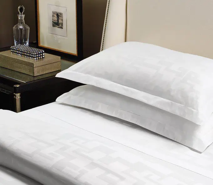 Luxurious hotel linen on a cozy guest bed with a well-appointed nightstand.