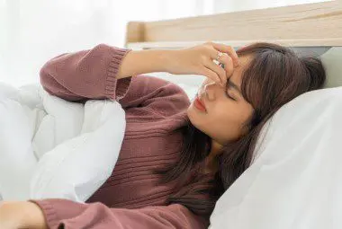 Woman with allergies lying in a hotel bed.