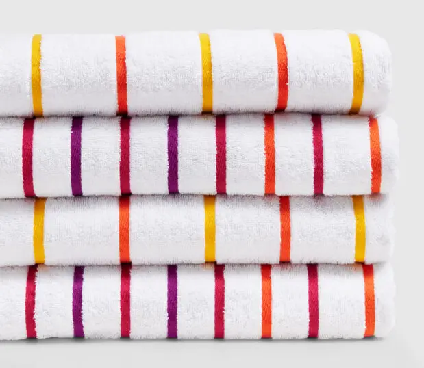 A stack of vibrant sunrise striped pool towels.