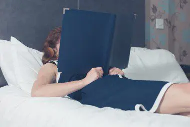 Women looking at a pillow menu while lying in a hotel bed.