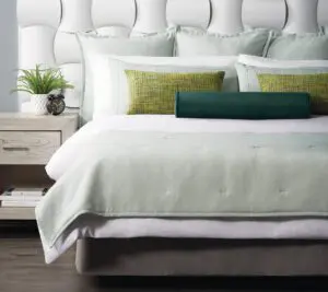 Custom Top of Bed featuring ImagePoint pillows on a white bed with a pale green throw and shams.