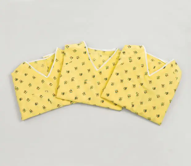 Three Risk Identity Patient Gowns folded and laying in a semi-circle. The pattern for this hospital gown s Kaleidoscope Yellow color.