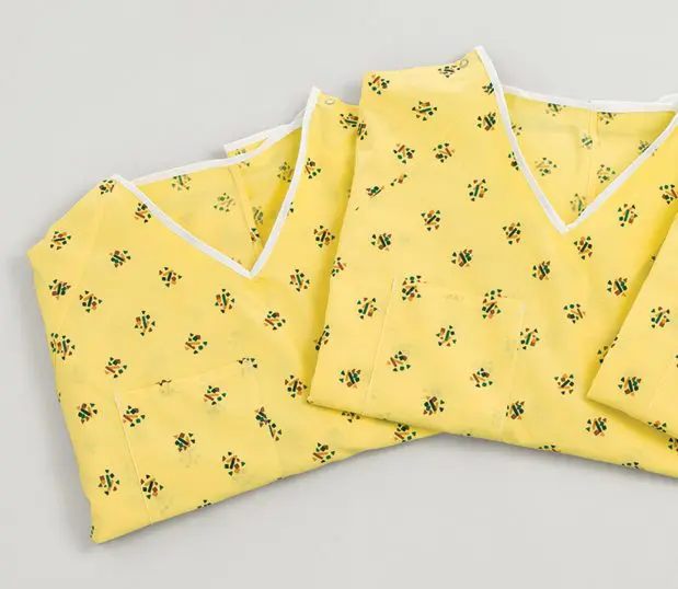 Detail of the pattern the Risk Identity Patient Gown. Kaleidoscope Yellow has a yellow background with clusters of squares, triangles and rectangles in bright colors.
