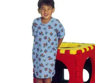 Image is of a boy standing in front of a large block wearing our toddler hospital gowns in the blue Happy Hound print. are made from ChildGuard™ Fabric and feature a variety of diverse color prints that are sure to make young patients smile.