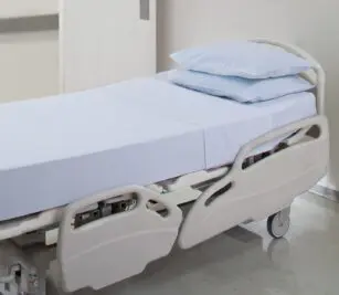 PerVal® Woven Sheeting for hospitals and health systems. Available in flat sheet, pillowcase, contour sheet, or draw sheet. Shown here on a hospital bed.