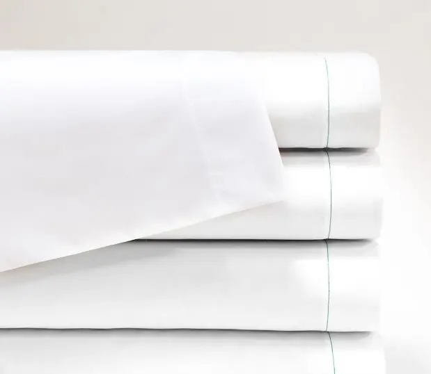 T-130 Woven Sheeting for hospitals and health systems for healthcare bedding. Available in flat sheets, contour sheets, drawsheets, or pillowcases. Shown in a folded stack in the color Bleached White.