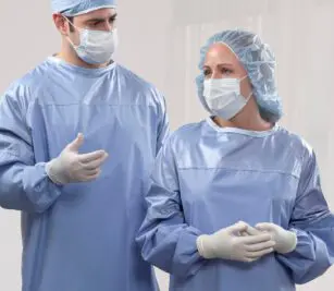 This image shows two doctors in masks, head coverings, surgical gloves and wearing the blue ComPel® XTR Reusable Surgical Gowns.