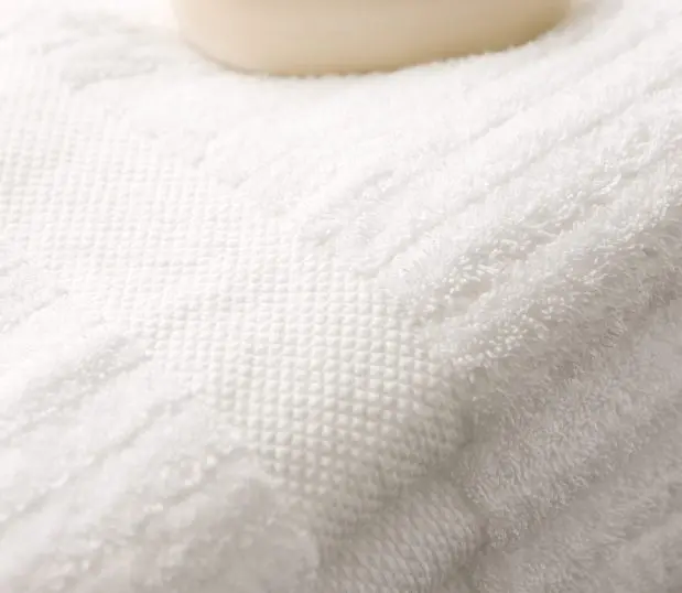 This image shows a detail of luxurious striped bath towels with a bar of soap in the background.