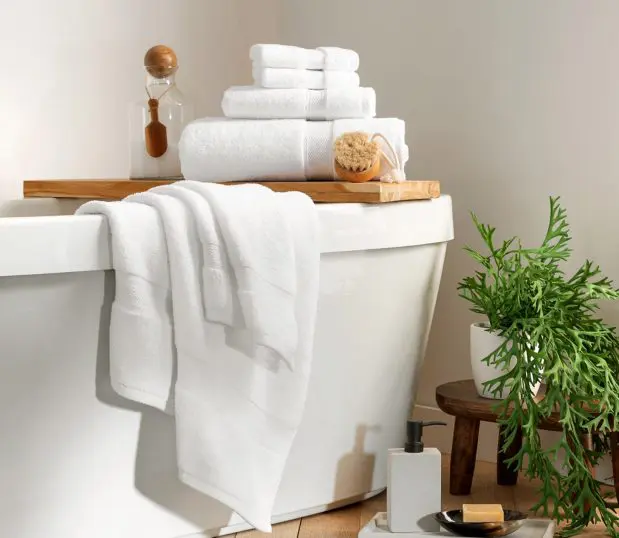 Lynova® uses luxurious, low twist microcotton to create the softest towels in hospitality. Image shows a stack of Lynova towels in a bathroom setting.