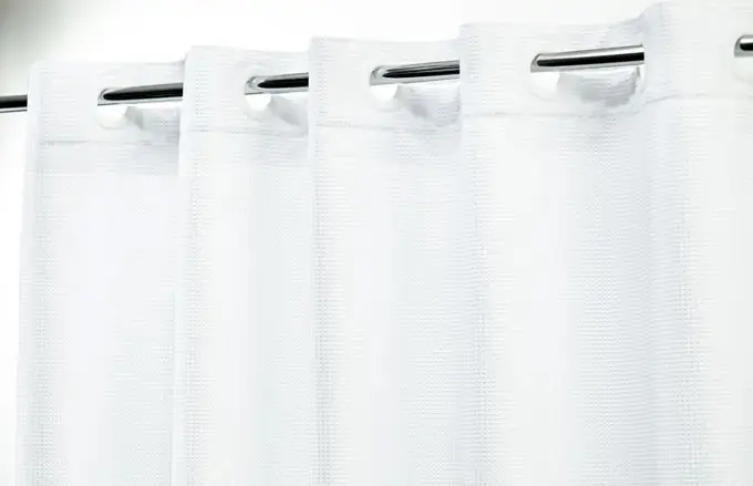 Hook-free shower curtain in Lux Waffle in the color white hanging from a standard shower curtain rod.