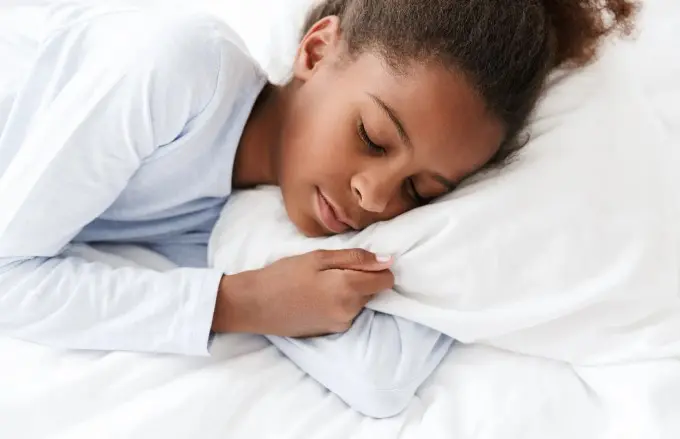 A young woman sleeping in a hotel bed with comfortable pillows.