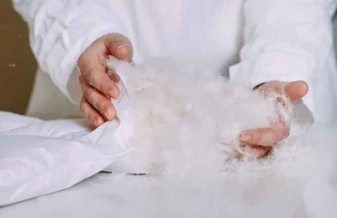 A technician stuffs a comforter with feather and down material.