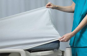 A DermaTherapy fitted sheet being placed on a patient bed.