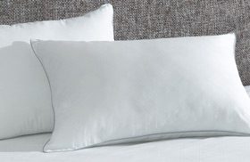 AllerEase Ultimate Pillows stacked on a hotel bed