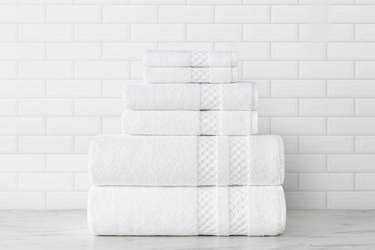 A stack of folded Capitol Towels with a white subway tile background.