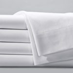 A stack of folded bed sheets, an additional folded sheets is draped over the top of the stack.