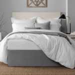 A well-made hotel bed, the duvet pulled up over one corner to showcase a graphite colored Circa Bed Wrap.