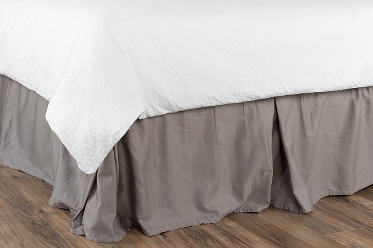 Image of a bed with a traditional messy bed skirt.