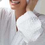 A smiling woman wearing a Cumulus hotel robe.