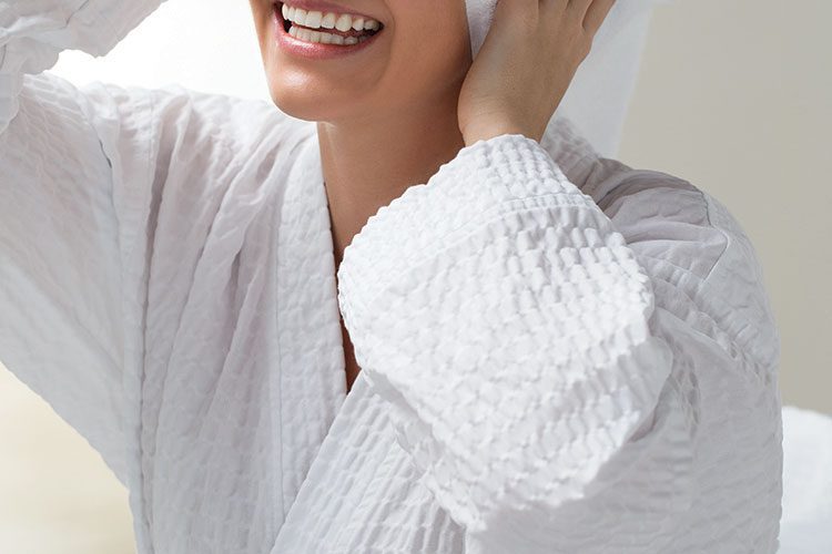 A smiling woman wearing a Cumulus hotel robe.