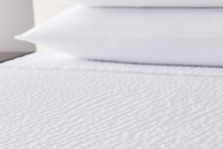 A detail shot of a bed featuring a Cumulus top cover.