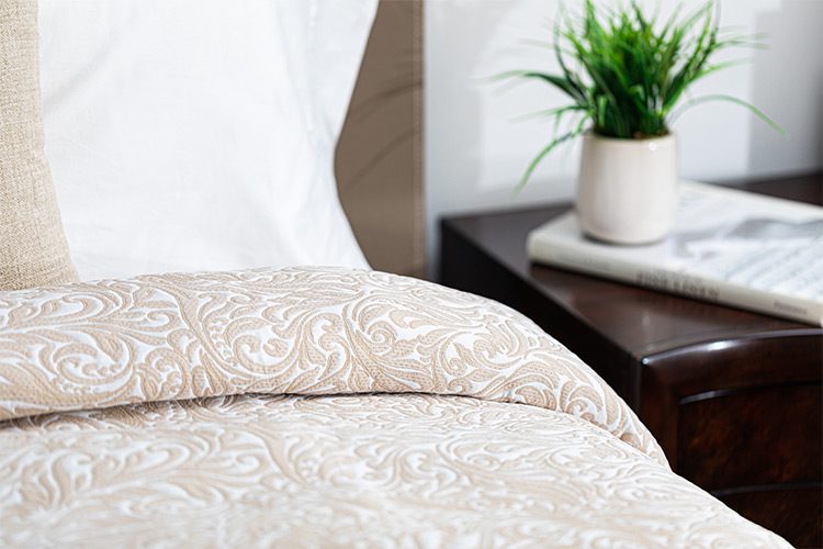 Image is of a beige custom healthcare bedspread. The fabric is Tudor.