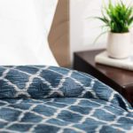 The image is of a dark blue custom healthcare bedspread with a criss-cross design. The fabric is called Melrose.