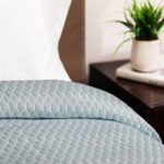 Image is of a teal custom healthcare bedspread. The pattern is called Embrace.