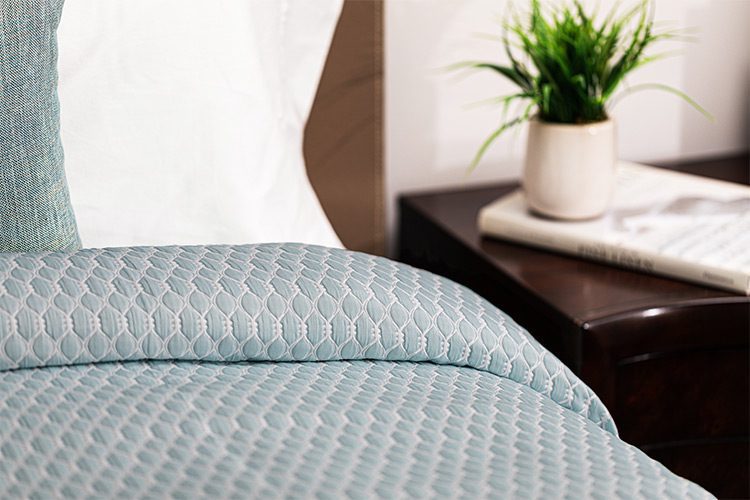 Image is of a teal custom healthcare bedspread. The pattern is called Embrace.