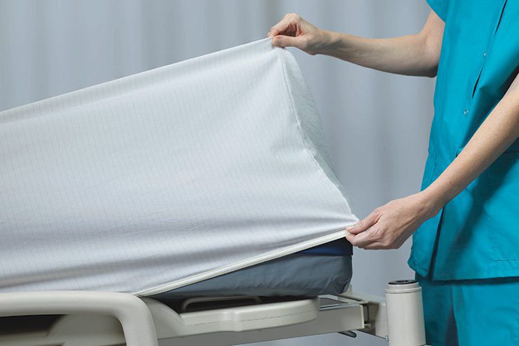 FDA-cleared DermaTherapy® therapeutic sheet being placed on a hospital bed by a clinician