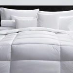 A well-made hotel bed featuring an Elevations comforter.