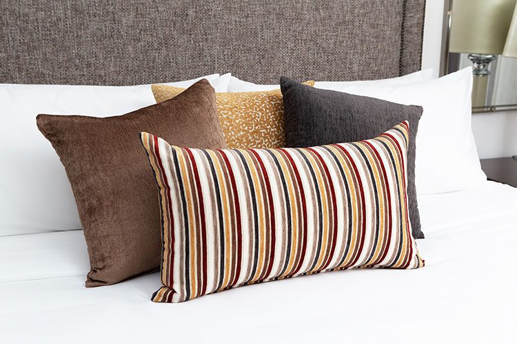 Four decorative throw pillows arranged on a hotel bed.