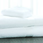 A stack of EuroClassique bath towels and a washcloth sit atop a marble countertop.
