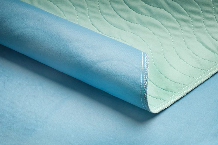 A close up image of EuroTech hospital bed pads. These reusable incontinence pads feature a 100% brushed polyester face fabric that is notable for both comfort and moisture-wicking performance. These lightweight reusable underpads are more comfortable for the patient and folds more consistently and efficiently in the laundry.