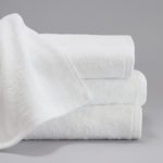 A ForeverSoft bath towel draped over a stack of three folded ForeverSoft bath towels.