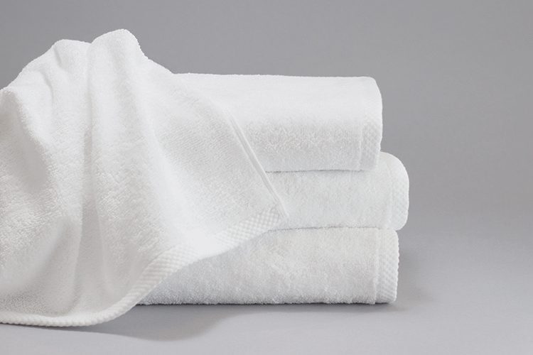 A ForeverSoft bath towel draped over a stack of three folded ForeverSoft bath towels.