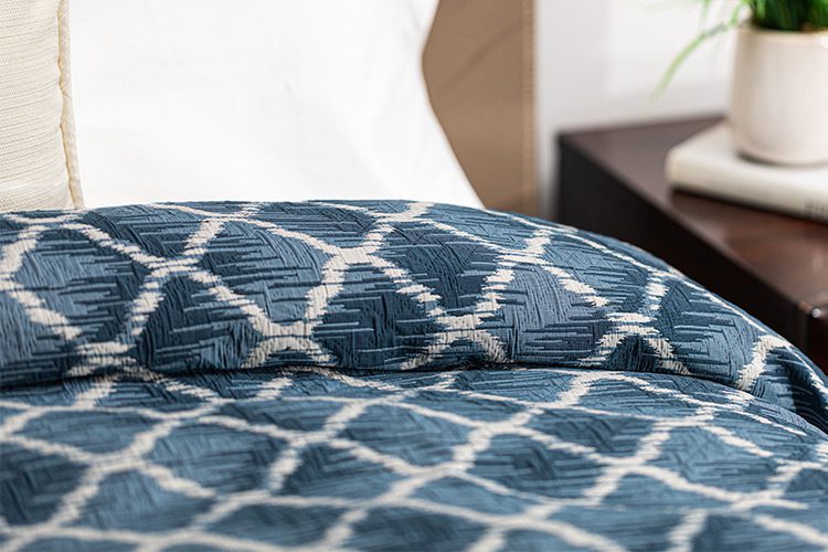 A close up image of a patient bed featuring a blue patterned bed spread.