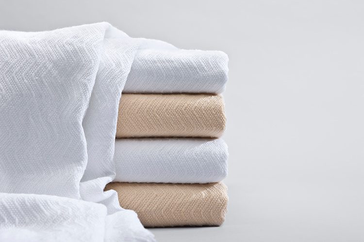 A stack of herringbone blankets in bleached and natural.
