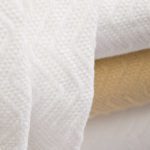 Detail of a stack of herringbone blankets in bleached and natural.